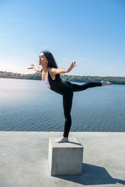 Jonge brunette vrouw beoefenen van yoga vroeg in de ochtend voor werktijd. Concept van wellness en een gezonde levensstijl