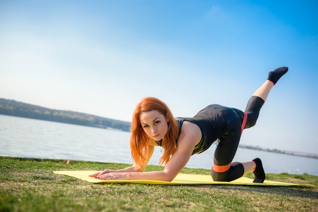 Jonge brunette vrouw beoefenen van yoga vroeg in de ochtend voor werktijd. Concept van wellness en een gezonde levensstijl