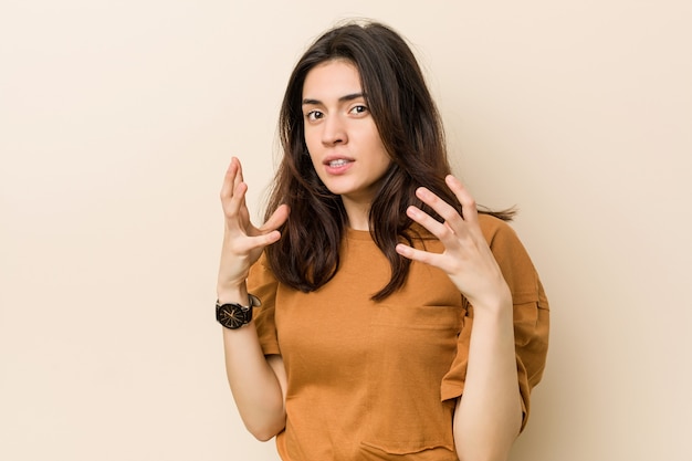 Jonge brunette vrouw boos schreeuwen met gespannen handen.