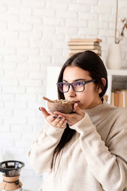 jonge brunette vrouw brouwen van koffie in coffemaker, groene koffiebonen ruiken