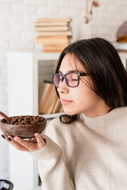 Jonge brunette vrouw brouwen van koffie in coffemaker, koffiebonen ruiken