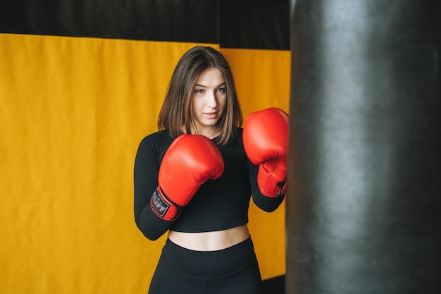 Jonge brunette vrouw in het zwart draagt een betrokken bokstraining in de sportschool van de fitnessclub