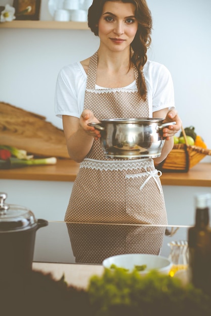 Foto jonge brunette vrouw kokende soep in de keuken. voedsel en gezondheidsconcept.