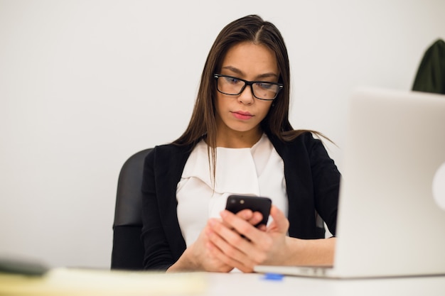 Jonge brunette vrouw met behulp van een telefoon op het werk