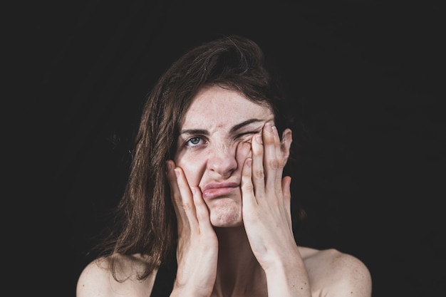 Jonge brunette vrouw met handen op haar gezicht