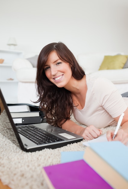 Jonge brunette vrouw ontspannen met haar laptop en poseren tijdens het schrijven op een notebook