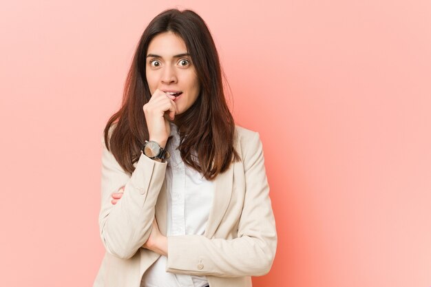 Jonge brunette zakenvrouw tegen een roze achtergrond nagels bijten, nerveus en erg angstig.