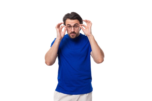 Jonge brute brunette man met een baard in een T-shirt op een witte achtergrond met kopieerruimte