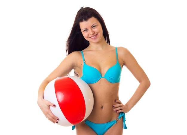 Jonge charmante vrouw met lang donker haar in blauw zwempak met roodwitte bal in studio