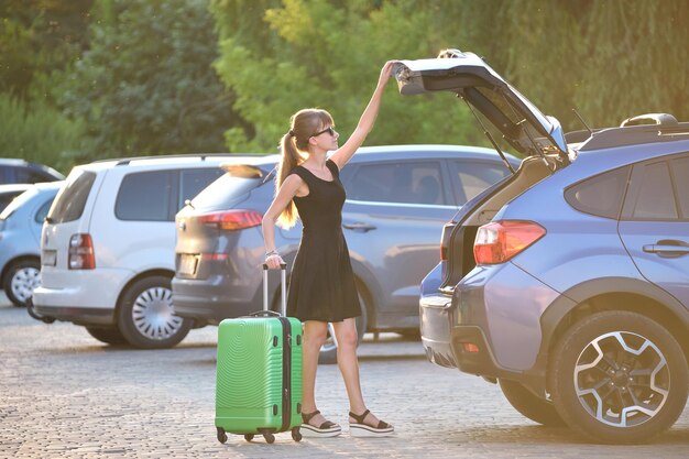 Jonge chauffeur die een kofferzak uit haar auto haalt Reizen en vakantie concept