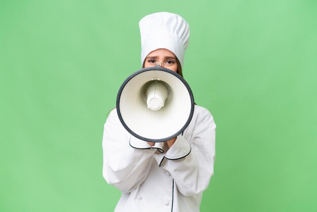 Jonge chef-kok blanke vrouw over geïsoleerde achtergrond die door een megafoon schreeuwt