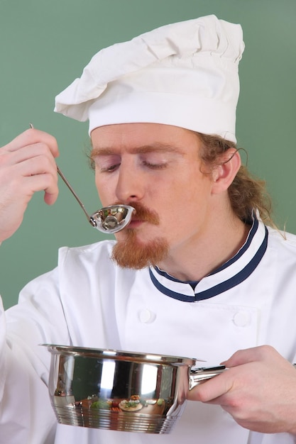 Jonge chef-kok die eten proeft met een eetlepel