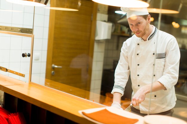 Jonge chef-kok die voedsel in de keuken voorbereidt