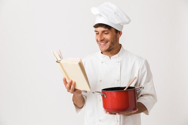 Jonge chef-kok man geïsoleerd op een witte muur koken.