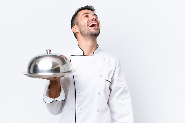 Jonge chef-kok met dienblad dat op witte achtergrond wordt geïsoleerd