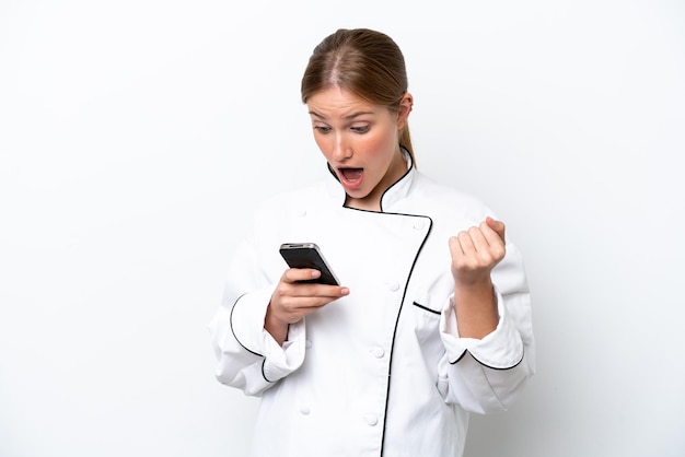 Jonge chef-kok vrouw geïsoleerd op een witte achtergrond verrast en het verzenden van een bericht