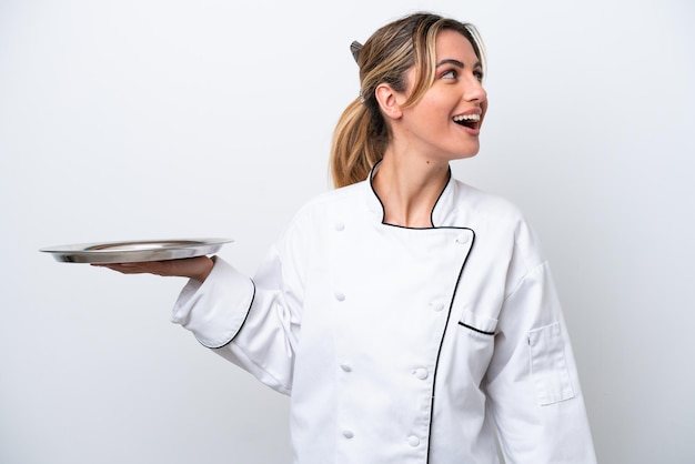 Jonge chef-kok vrouw met dienblad geïsoleerd op een witte achtergrond lachen in zijpositie