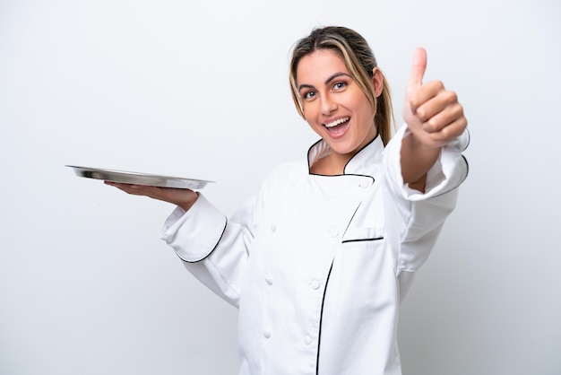 Jonge chef-kok vrouw met dienblad geïsoleerd op een witte achtergrond met duimen omhoog omdat er iets goeds is gebeurd