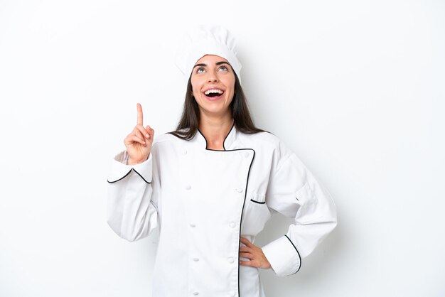 Jonge chef-kokvrouw over witte achtergrond die omhoog wijst en verrast