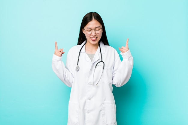 Jonge Chinese artsenvrouw die rotsgebaar met vingers tonen