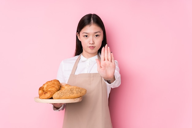 Jonge chinese bakkersvrouw geïsoleerde status met uitgestrekte hand die eindeteken toont, die u verhinderen.