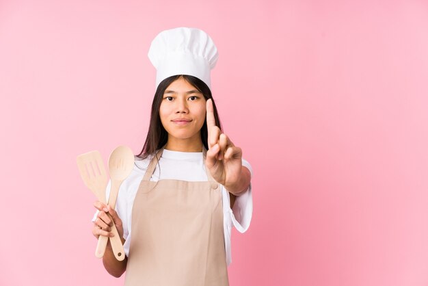 Jonge Chinese geïsoleerde chef-kokvrouw die nummer één met vinger toont.