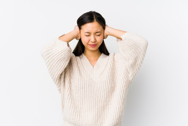 Jonge Chinese geïsoleerde vrouw behandelend oren met handen die niet te hard geluid proberen te horen.