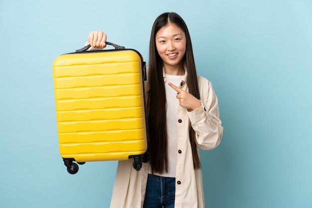 Jonge Chinese jonge vrouw die met reiskoffer wordt geïsoleerd