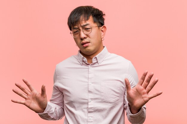 Jonge Chinese mens die iets verwerpt dat een gebaar van afschuw doet