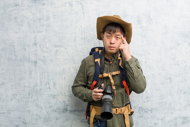 Jonge Chinese ontdekkingsreizigermens die een camera houden denkend over een idee