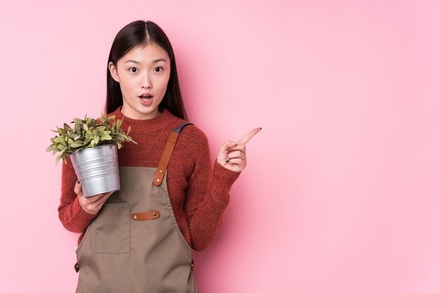Jonge Chinese tuinmanvrouw die een installatie geïsoleerd houden richtend aan de kant