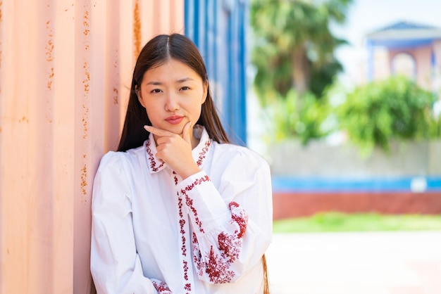 Jonge Chinese vrouw die buitenshuis denkt