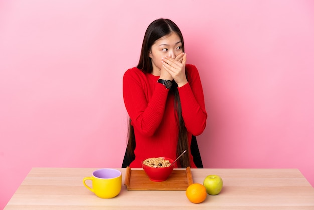 Jonge Chinese vrouw die ontbijt in een lijst heeft die mond behandelt en aan de kant kijkt