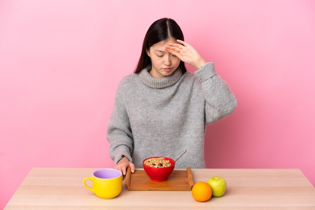 Jonge Chinese vrouw die ontbijt in een lijst met vermoeide en zieke uitdrukking heeft