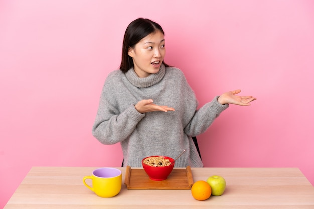 Jonge Chinese vrouw die ontbijt in een lijst met verrassingsuitdrukking heeft terwijl het kijken kant