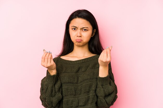 Jonge Chinese vrouw die op een roze muur wordt geïsoleerd die aantoont dat zij geen geld heeft.