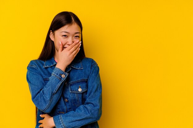 Jonge chinese vrouw die op gele muur wordt geïsoleerd die gelukkige, zorgeloze, natuurlijke emotie lacht