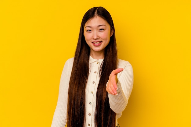 Jonge chinese vrouw die zich uitstrekt hand op camera in groetgebaar.