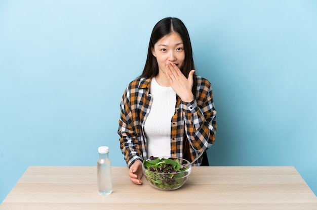 Jonge Chinese vrouw een gelukkig salade eten en glimlachend die mond behandelen met hand