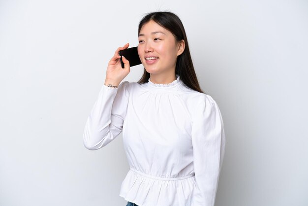 Jonge Chinese vrouw geïsoleerd op een witte achtergrond die een gesprek voert met de mobiele telefoon