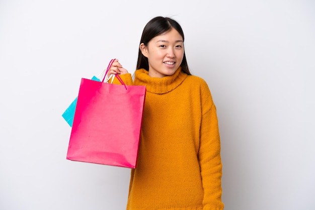Jonge Chinese vrouw geïsoleerd op een witte achtergrond met boodschappentassen en glimlachend