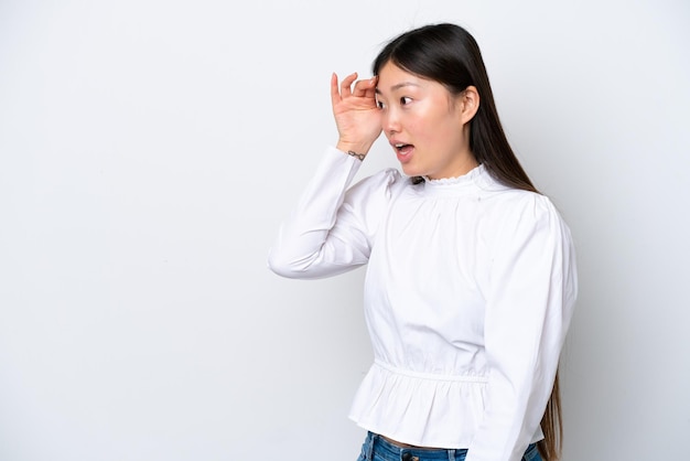 Jonge Chinese vrouw geïsoleerd op een witte achtergrond met verbazing uitdrukking terwijl ze opzij kijkt