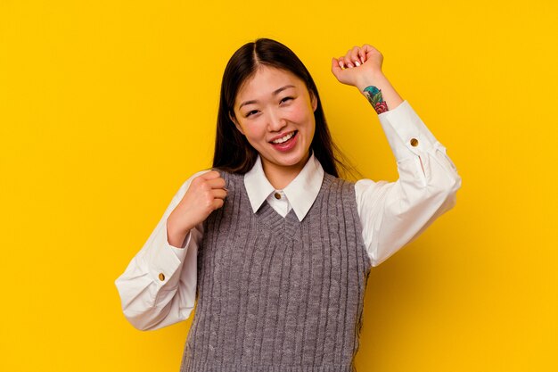 Jonge chinese vrouw geïsoleerd op gele achtergrond dansen en plezier maken.