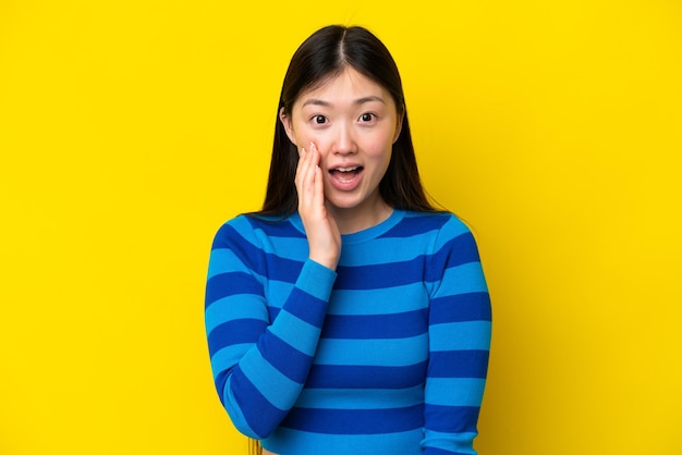 Jonge Chinese vrouw geïsoleerd op gele achtergrond met verrassing en geschokte gezichtsuitdrukking