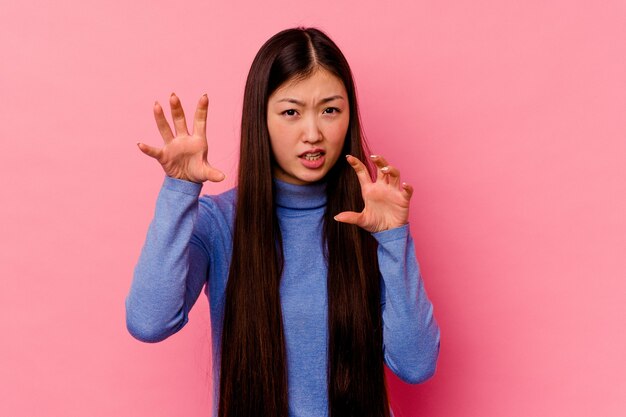 Jonge chinese vrouw geïsoleerd op roze achtergrond boos schreeuwen met gespannen handen.