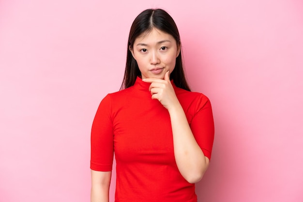 Jonge Chinese vrouw geïsoleerd op roze achtergrond denken