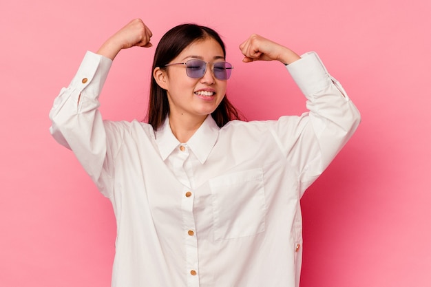 Jonge chinese vrouw geïsoleerd op roze achtergrond die een speciale dag viert, springt en armen met energie opheft.