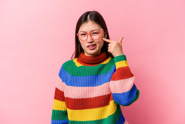 Jonge Chinese vrouw geïsoleerd op roze achtergrond die oren bedekt met handen