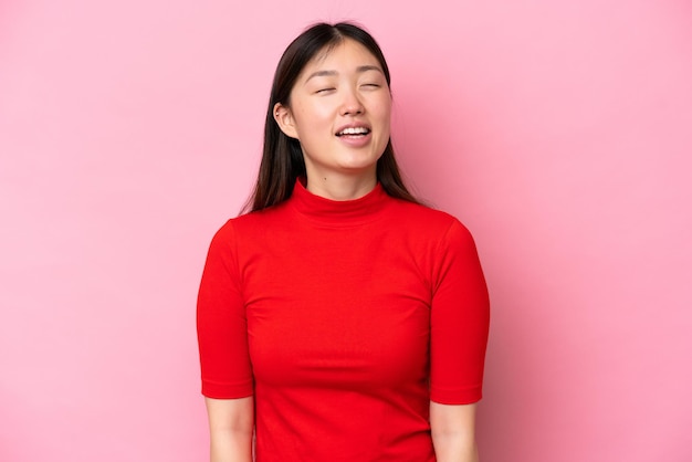 Jonge Chinese vrouw geïsoleerd op roze achtergrond lachen