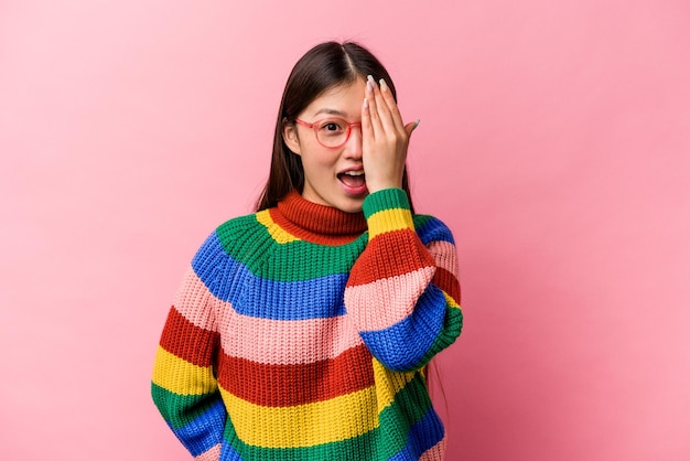 Jonge Chinese vrouw geïsoleerd op roze achtergrond met plezier die de helft van het gezicht bedekt met palm